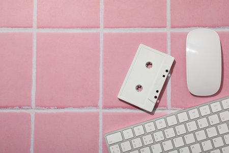 Computer keyboard with mouse and cassette on a pink backgroundの写真素材