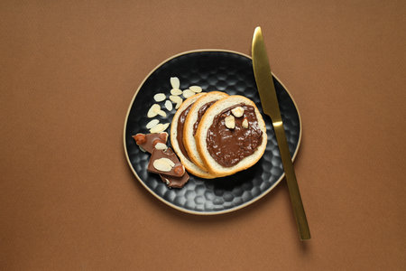Bread with chocolate paste in a bowl on a brown backgroundの写真素材