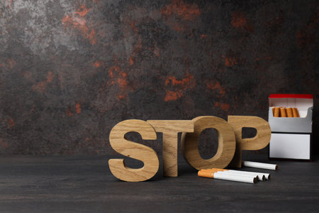 The word stop with a pack of cigarettes on a dark backgroundの写真素材