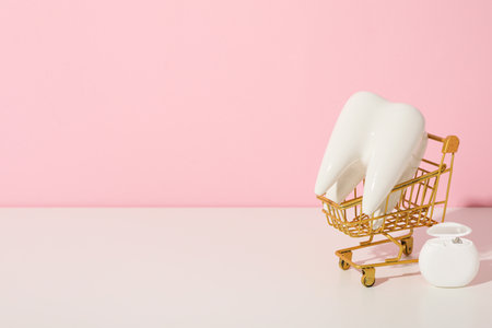A tooth in a shopping cart on a pink background.の写真素材