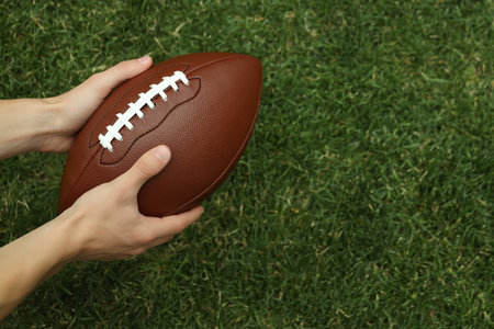 A brown rugby ball in the hands of a man
