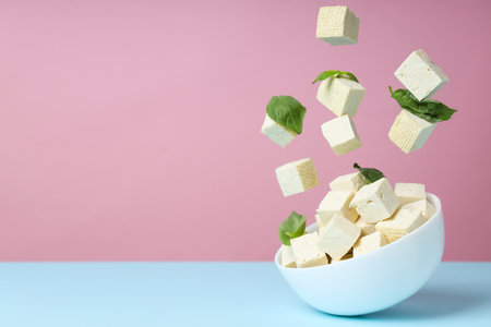 Cubes of tofu in a bowl on a pink backgroundの写真素材