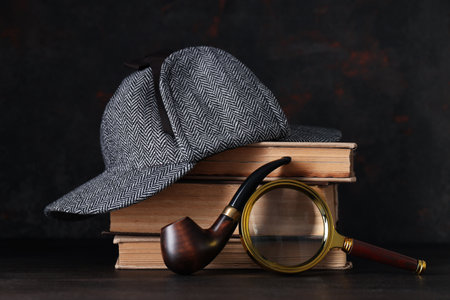 Magnifying glass with fingerprints, books and hat