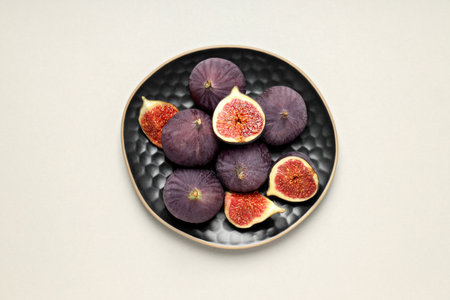 Fresh ripe figs in black bowls on white background