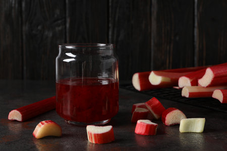 Rhubarb jelly in a jar with fresh rhubarb stems on a dark backgroundの写真素材