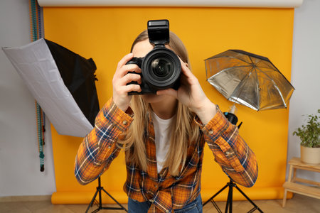 Beautiful girl photographer in the photo studio, on a yellow background.の写真素材