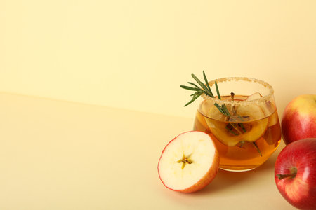 Red apples and glass with apple cider on beige background, space for textの写真素材