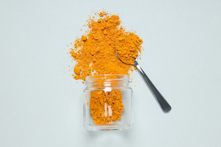 Turmeric powder in a jar on a light backgroundの写真素材