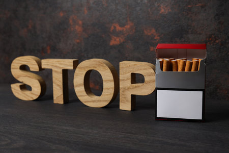 The word stop with a pack of cigarettes on a dark backgroundの写真素材
