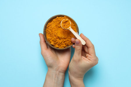 Turmeric powder in a bowl on a blue backgroundの写真素材