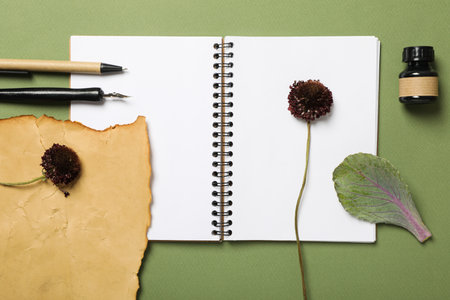 Herbarium of flowers, notepad and pen on green background, top view