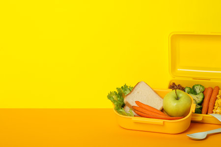 Yellow lunch box with food on a yellow backgroundの写真素材