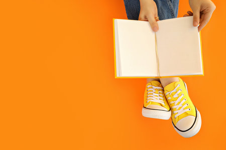 An open book in hands on a yellow backgroundの写真素材