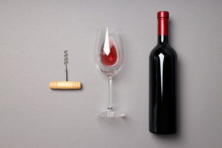 A bottle of wine, a glass and a corkscrew, on a gray background.の写真素材