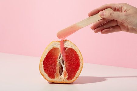 Wooden depilatory stick with fresh grapefruit on a pink backgroundの写真素材
