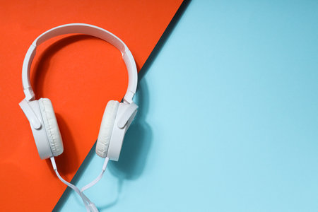 White, full-size wired headphones on a blue-orange background.の写真素材