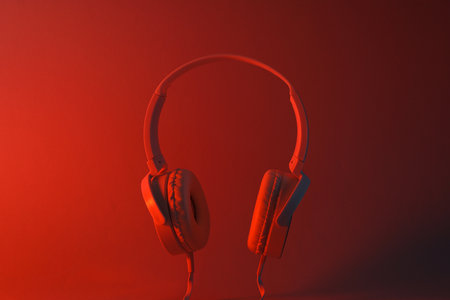 White, over-the-ear headphones with a wire on a colored, dark background.