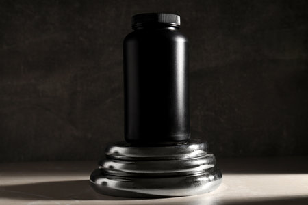 Black plastic jar on metal sport equipment on dark gray background, close upの写真素材