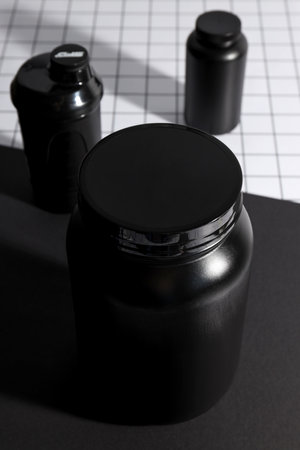 Black plastic jars and bottle on black and white background, close upの写真素材
