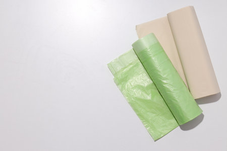 Rolls of garbage bags on white background, space for text