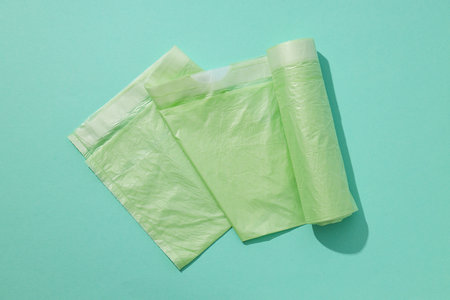 Rolls of garbage bags on green background, top view