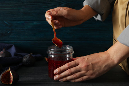 Figs, towel and jar of jam in hands on blue wooden backgroundの写真素材