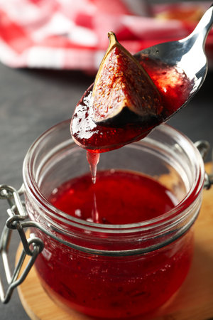 Jar of fig jam and spoon on gray background, close upの写真素材