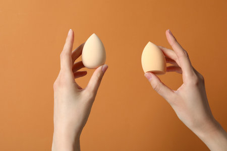 Makeup sponges in hand on a beige backgroundの写真素材