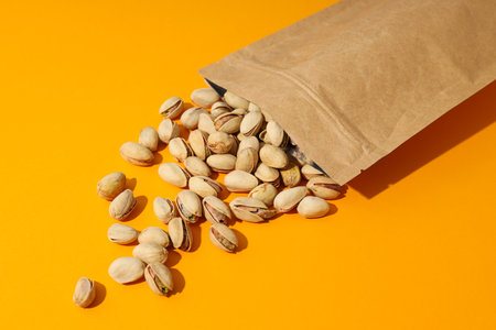 Pistachios in a craft bag, on a yellow background.の写真素材