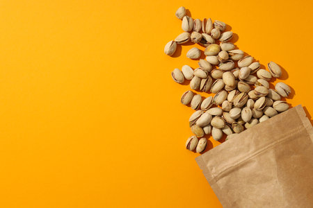 Pistachios in a craft bag, on a yellow background.の写真素材