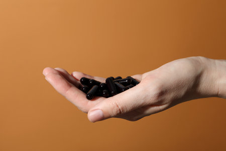 Tablets of activated carbon in hands, on a light background.の写真素材