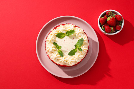 Red velvet cake on pink plate and berries on red background, top viewの写真素材