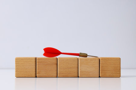 Five wooden cubes and red dart on white backgroundの写真素材