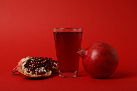 Pomegranate juice with fresh pomegranates on a red backgroundの写真素材