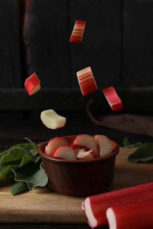 Chopped stalks of rhubarb in a bowl on a dark background