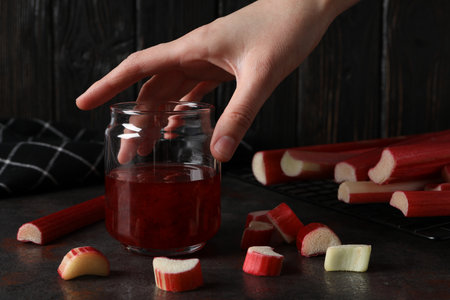 Rhubarb jelly in a jar with fresh rhubarb stems on a dark backgroundの写真素材