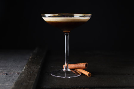 Martini espresso cocktail in glass and cinnamon sticks on dark backgroundの写真素材