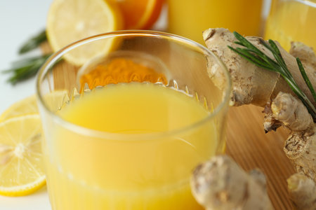 Glass with juice, wooden board and ingredients on white background, close upの写真素材