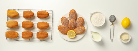 Madeleine cakes, butter, flour, milk and lemon on white background, top view
