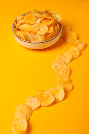 Potato chips in a bowl on a yellow backgroundの写真素材