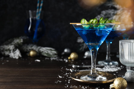 Blue cocktail in glasses, christmas tree branches with snow and balls on wooden background, space for textの写真素材