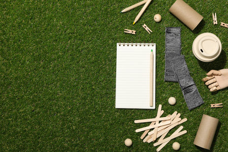Materials for upcycling, wooden hand and notepad on green background, space for textの写真素材