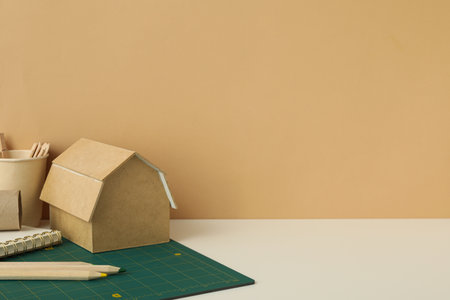 Paper cup, handmade house and notepad on beige background, space for textの写真素材