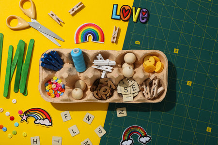 Art supplies in egg tray on yellow background, top viewの写真素材
