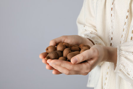 Ripe tamarind in female hands on a light backgroundの写真素材