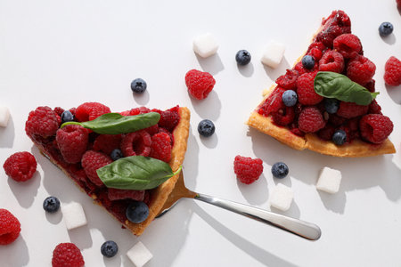 Pieces of berry pie, sugar and berries on white background, top view