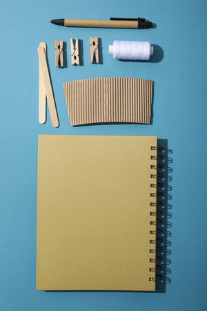 Notepad, wooden sticks, pen and thread on blue background, top view