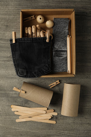 Pieces of denim fabric, paper rolls and box on wooden background, top view