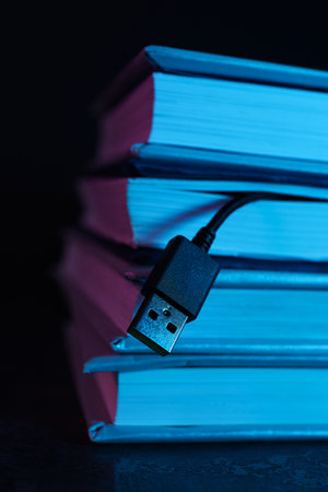 Books with a black USB cable on a dark background.の写真素材