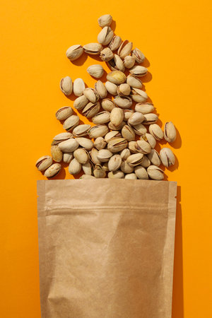 Pistachios in a craft bag, on a yellow background.の写真素材